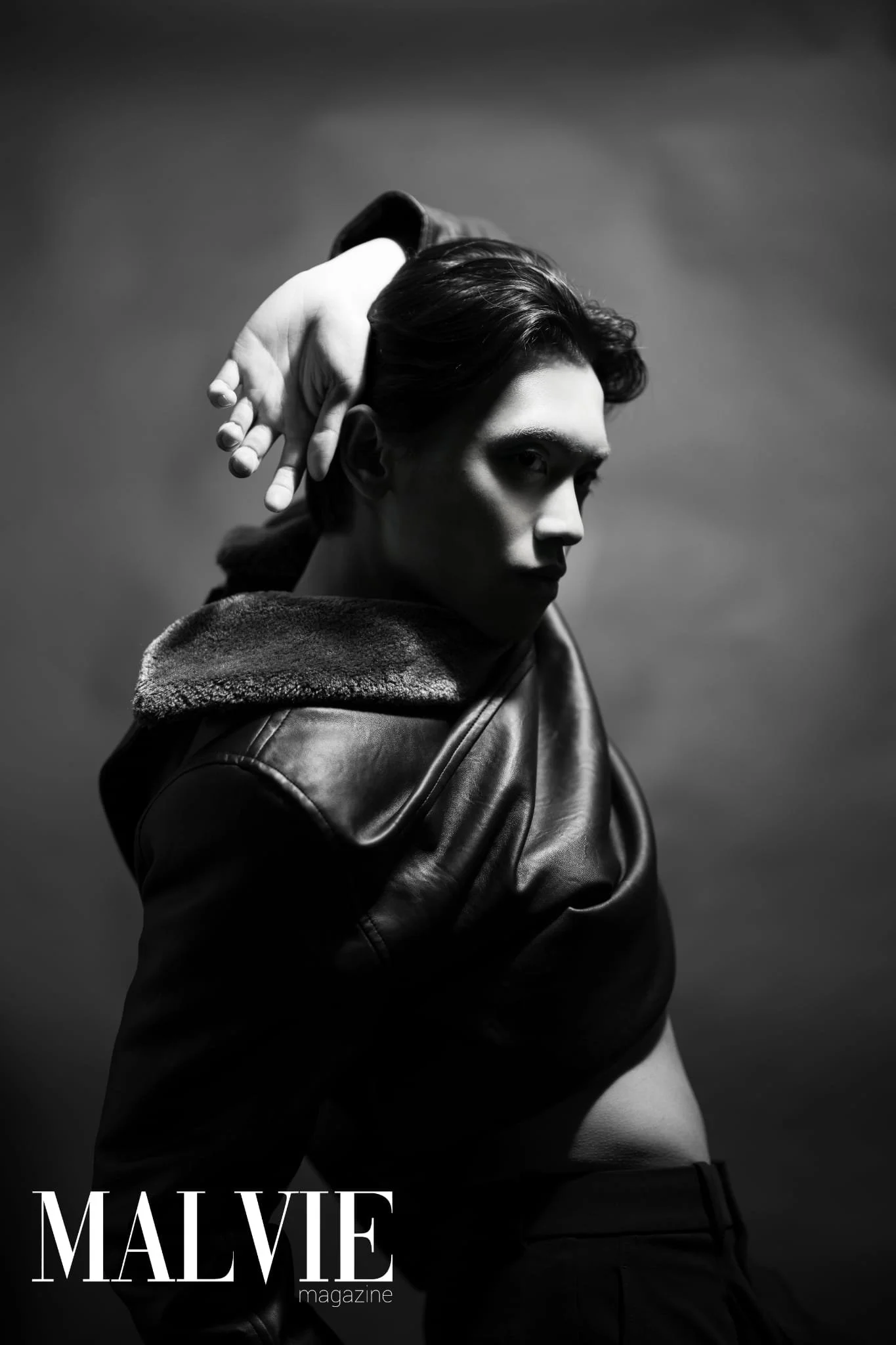 Black and white photo of a woman with short hair, wearing a leather jacket, looking over her shoulder with a serious expression. The magazine title 'MALVIE' is visible at the bottom of the image.