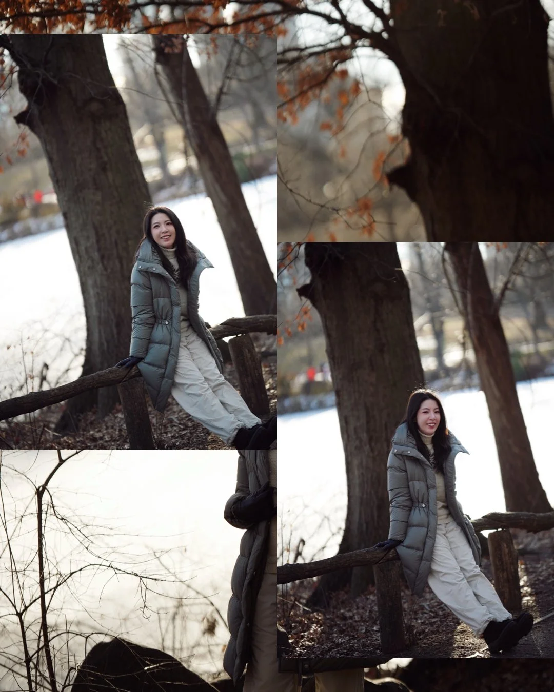 A young woman standing outdoors near a large tree during winter, wearing a gray coat, white pants, and black boots, smiling and leaning against a wooden fence.