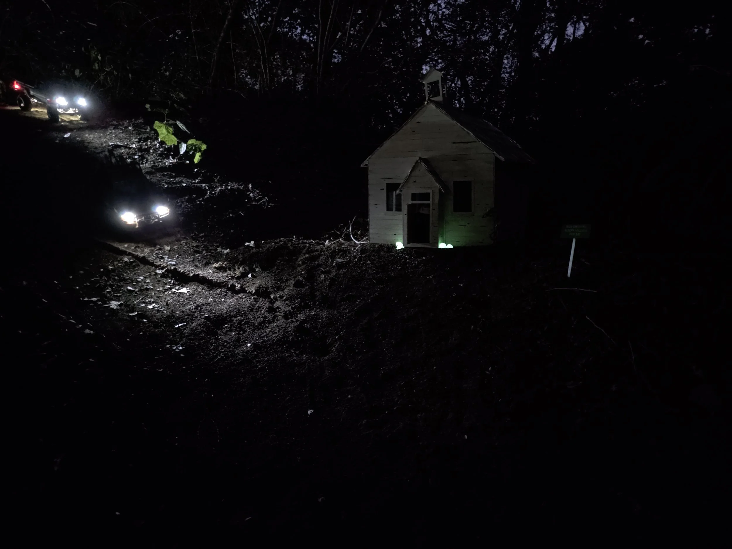 Headlights from Scale RC crawlers heading towards a scale church with steeple.