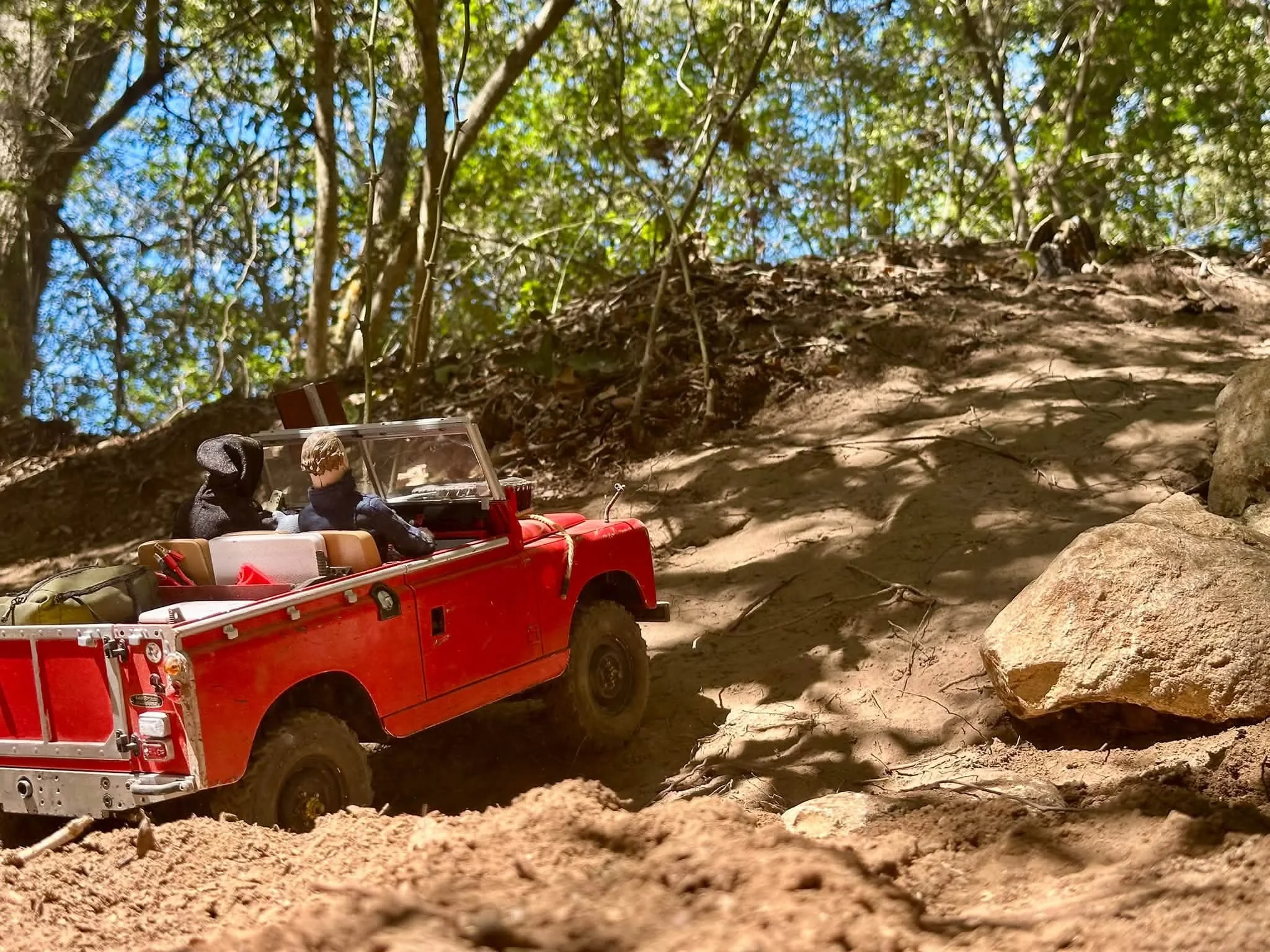 A red Boom RC truck with Halloween figures driving down a dirt road.  