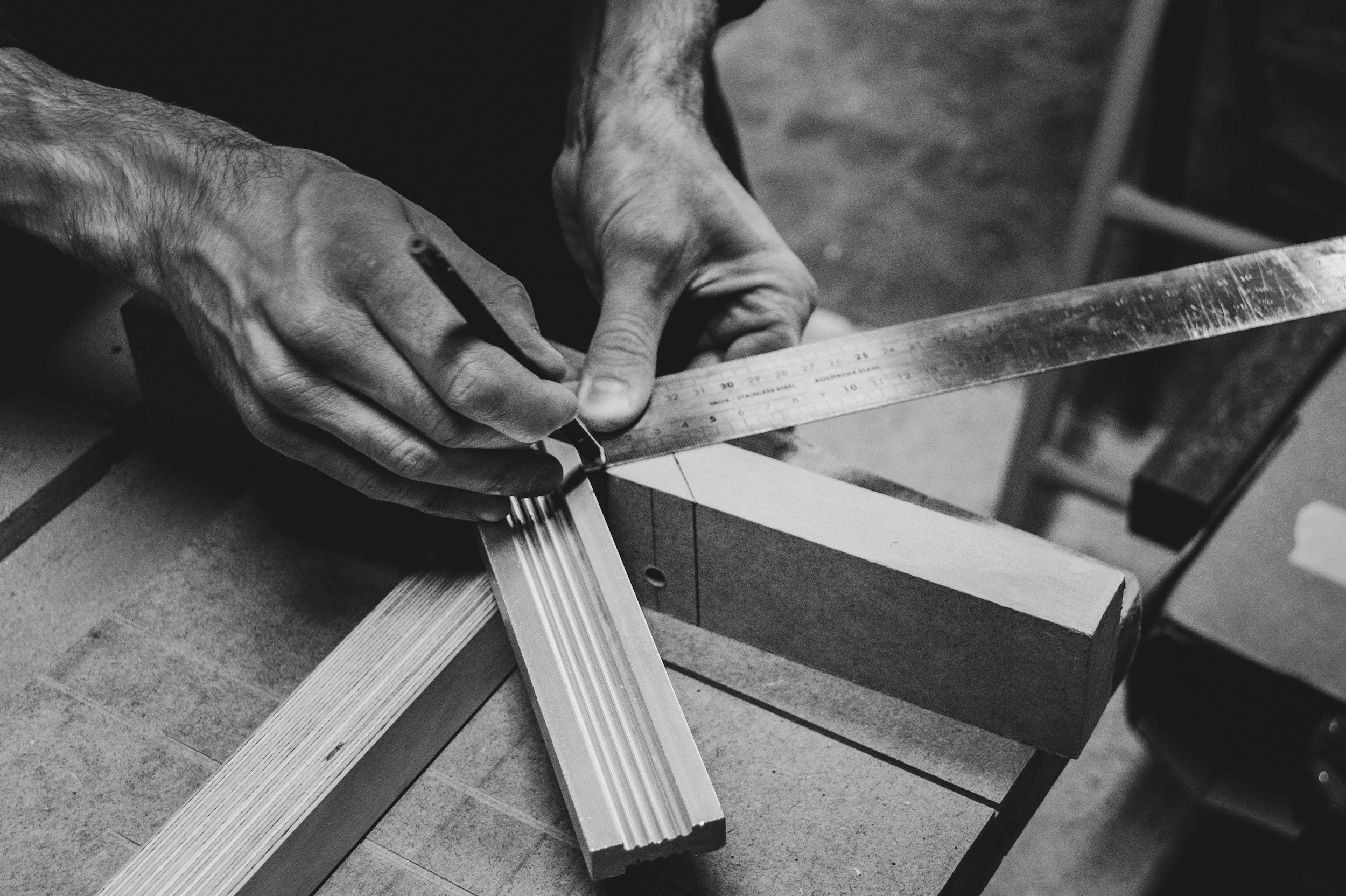 A person using a ruler to measure wood in a woodworking shop.