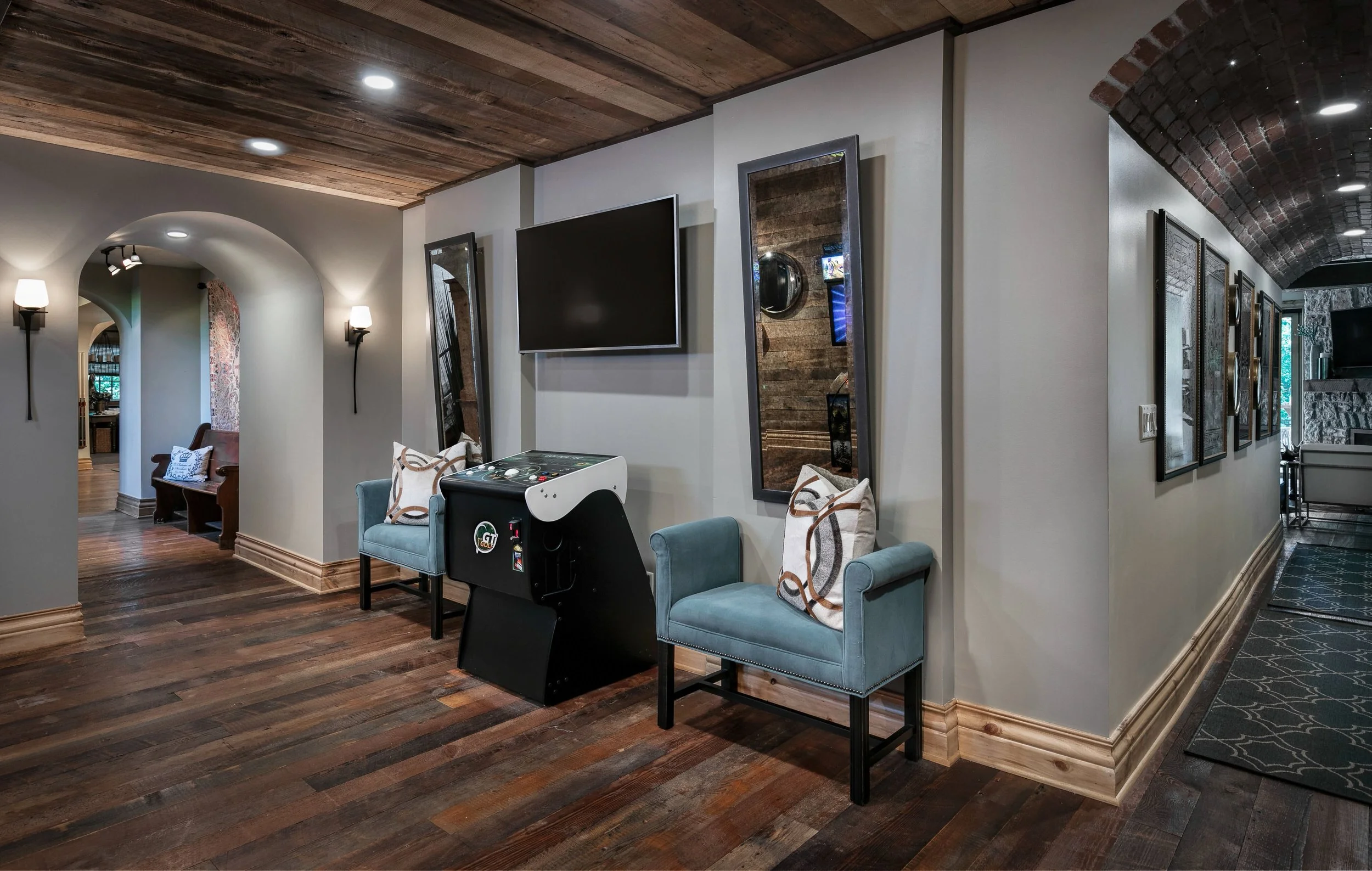 Basement entertaining space with reclaimed wood detailing, vaulted brick ceiling, and custom architectural features
