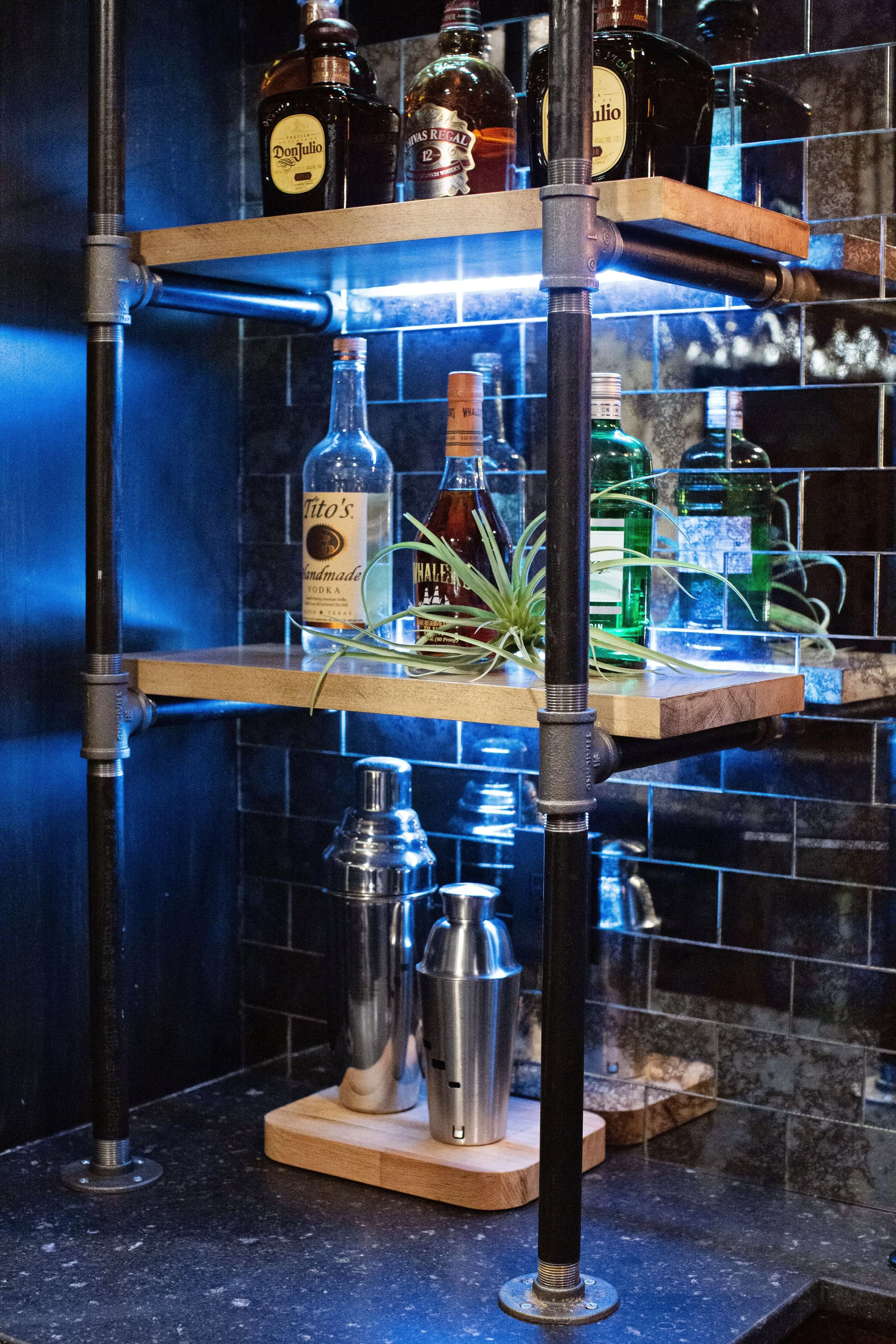 Luxury entertaining space with backlit bar shelving, dramatic tile detail, and moody contemporary finishes