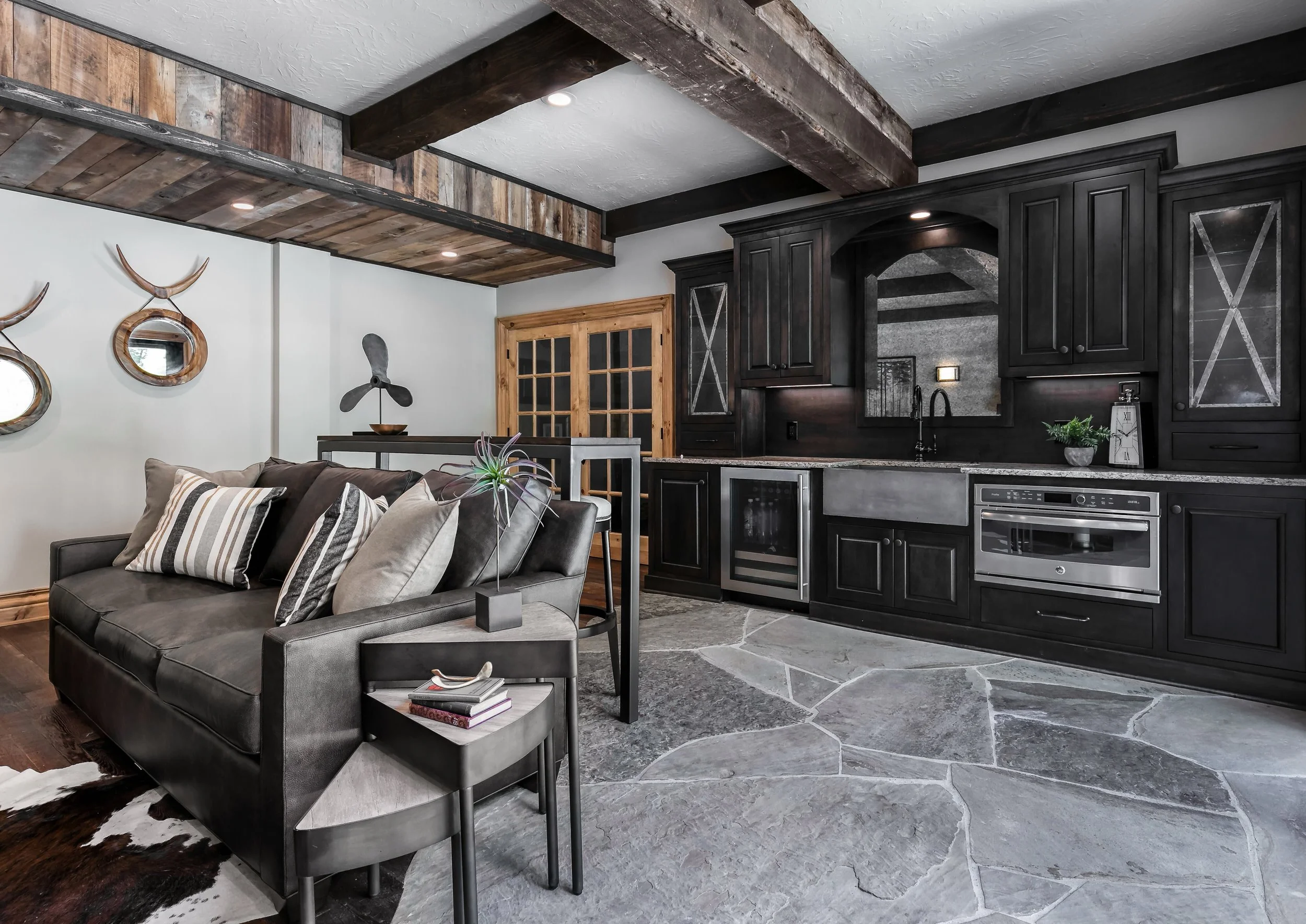 Rustic modern basement living space with dark cabinetry, layered textures, and integrated entertaining areas