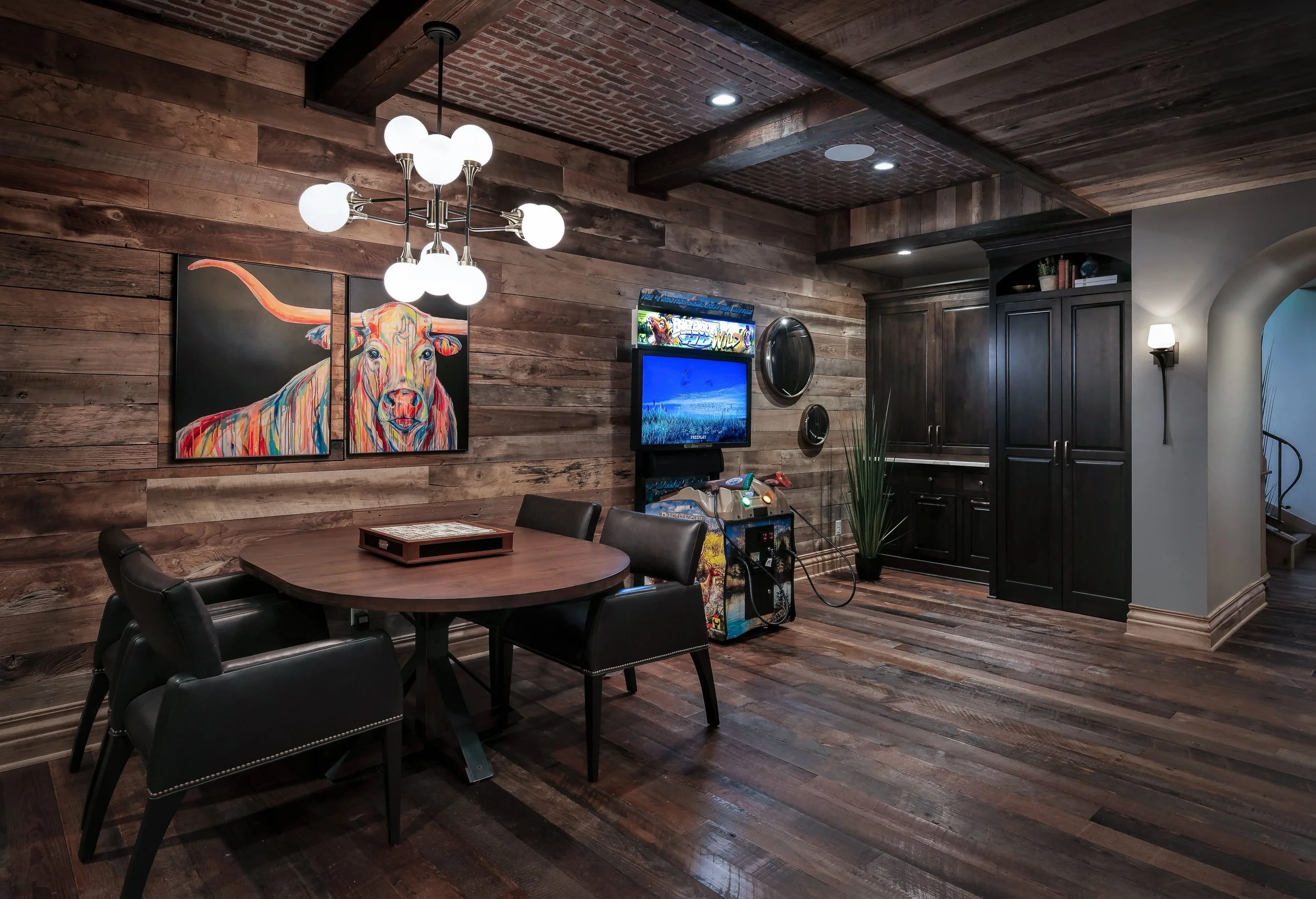 Rustic modern entertaining space with reclaimed wood finishes, statement lighting, and integrated gaming and media areas