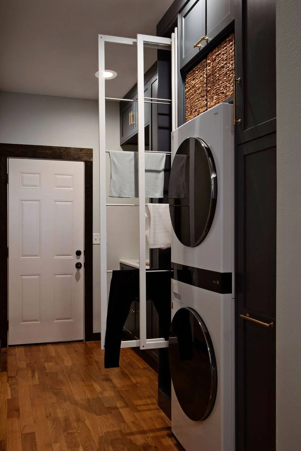 Custom laundry room design with stacked washer and dryer, built-in cabinetry, and warm wood detailing by Amy Krause Design