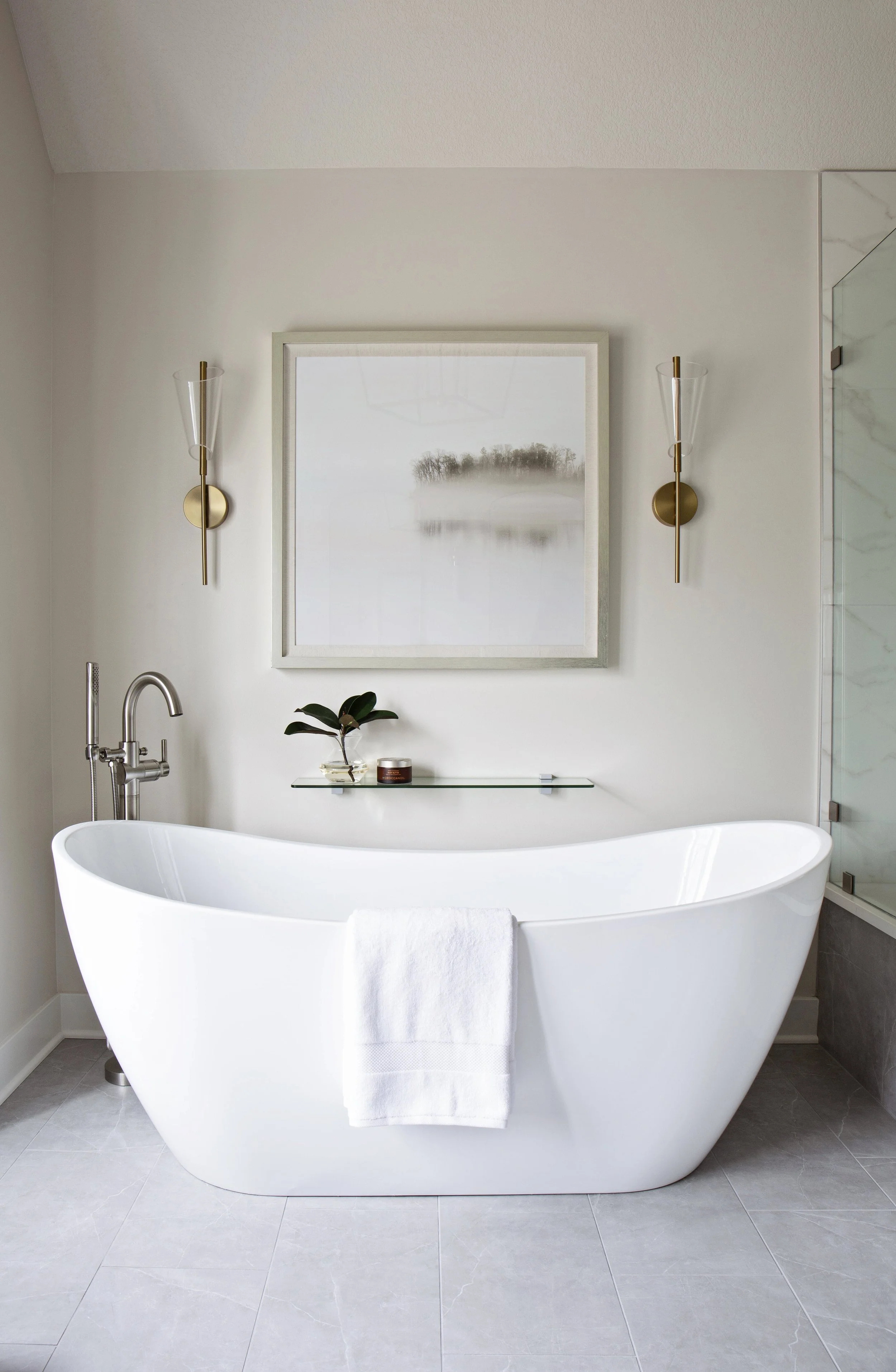 Luxury primary bathroom renovation with freestanding soaking tub, brass sconces, and soft neutral finishes by Amy Krause Design