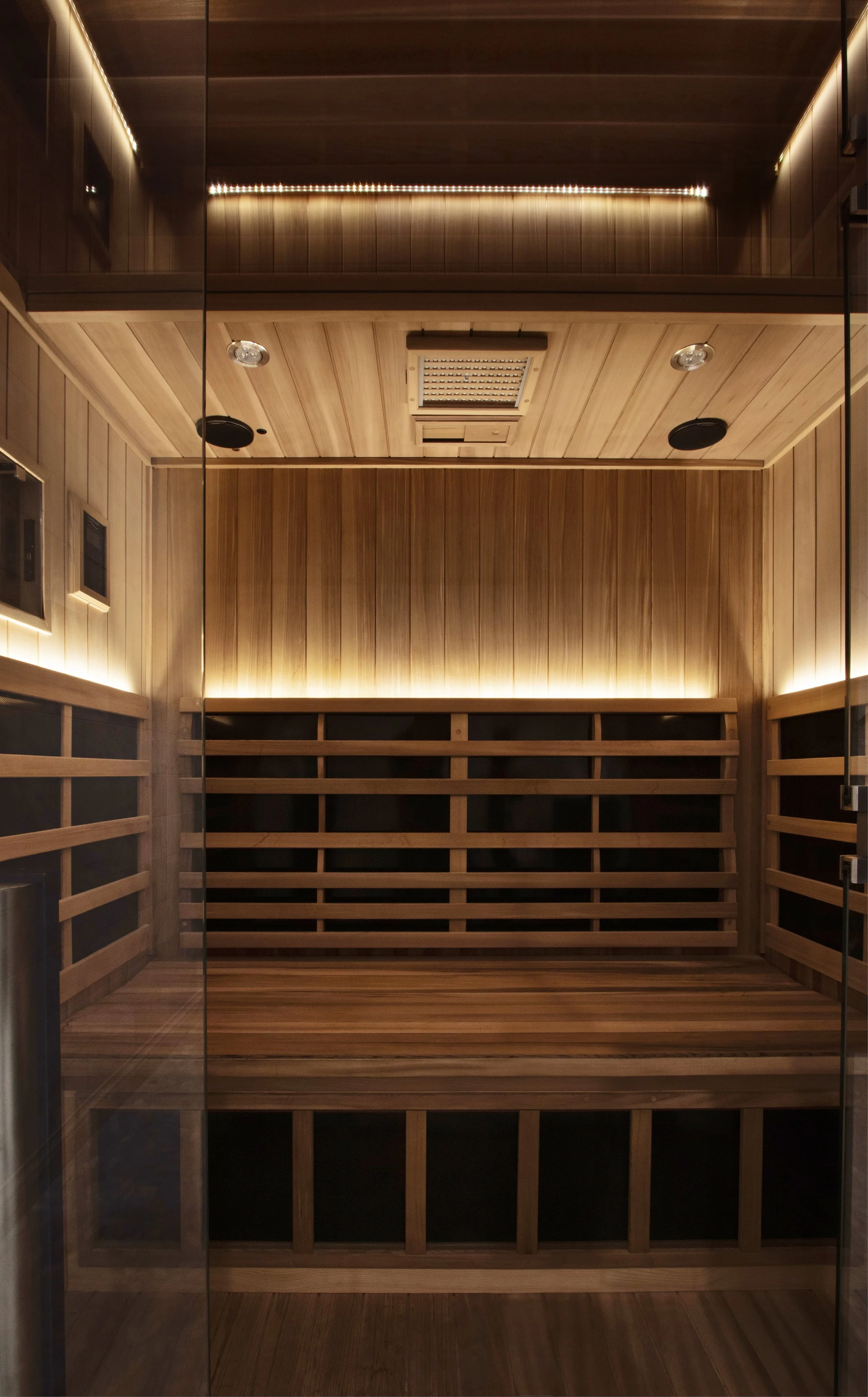 Luxury residential sauna with cedar paneling, built-in bench seating, and soft integrated lighting