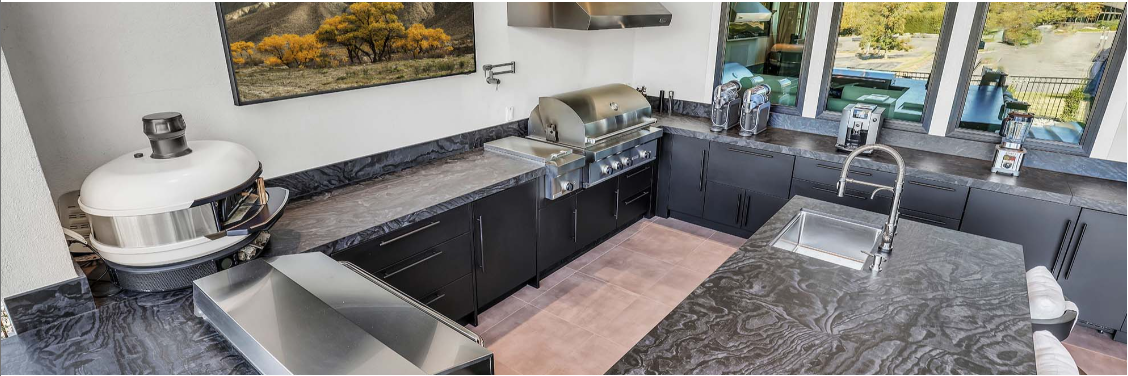 Outdoor kitchen with marine-grade stainless steel cabinetry, built-in grill, and sink designed for indoor-outdoor living.