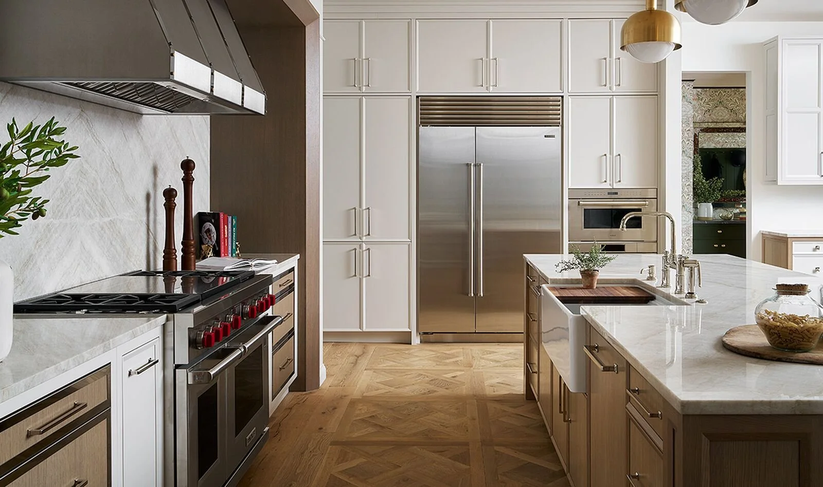Modern kitchen with white cabinets, stainless steel refrigerator, marble countertops, wooden flooring, and pendant lighting.