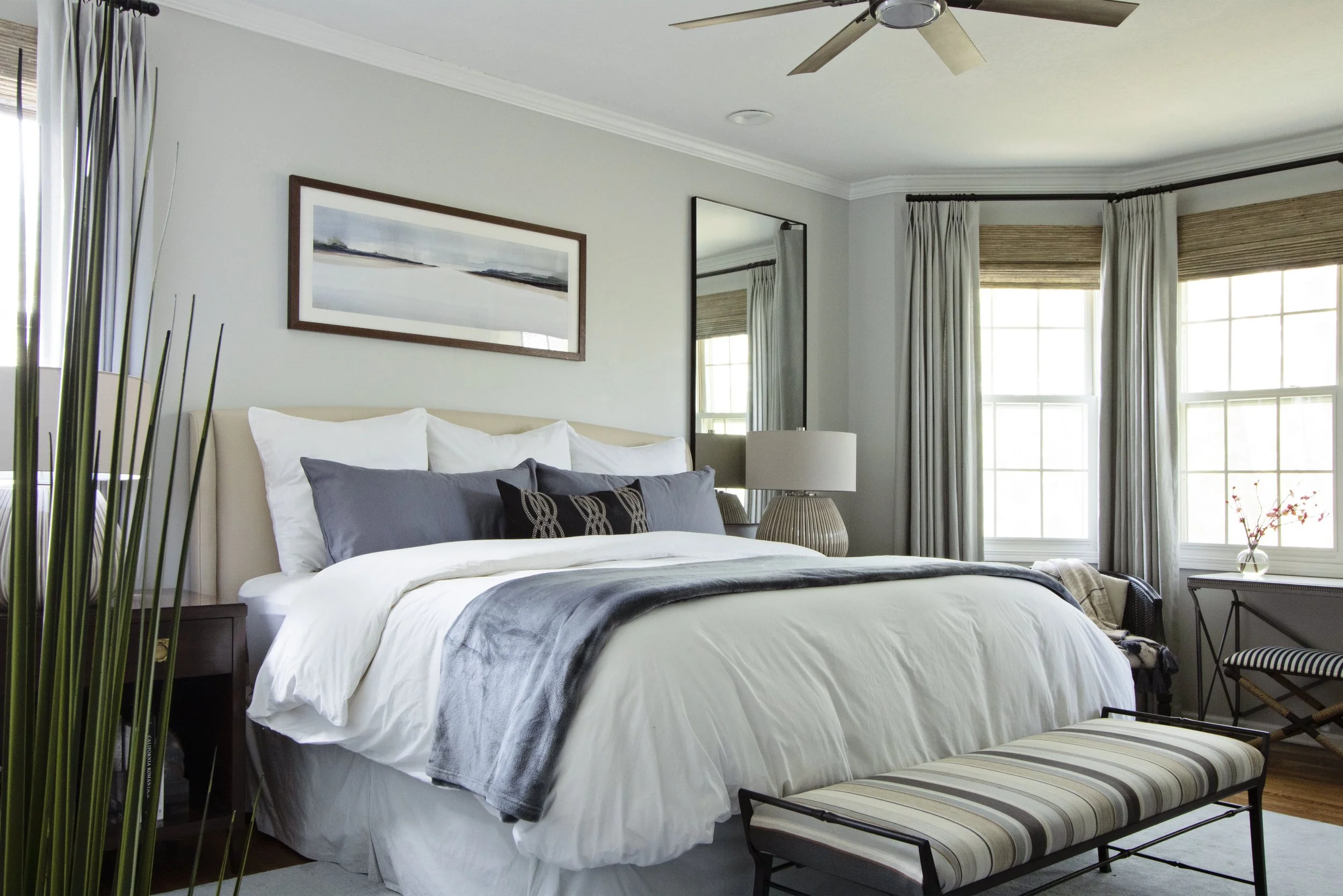 Serene bedroom retreat with upholstered bench, layered bedding, and warm transitional finishes