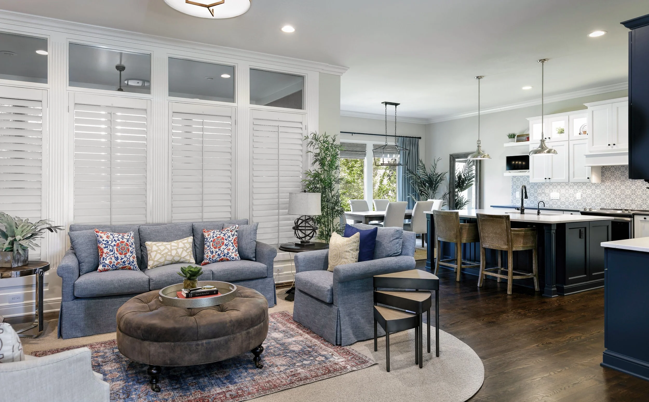 Bright open-concept kitchen and living space with custom cabinetry, navy island, and comfortable layered seating