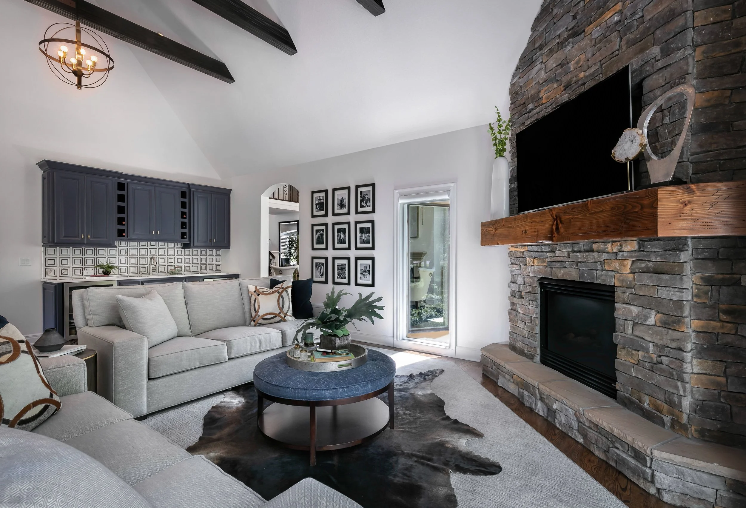 Luxury living space with architectural beams, dramatic stone fireplace, and tailored contemporary seating