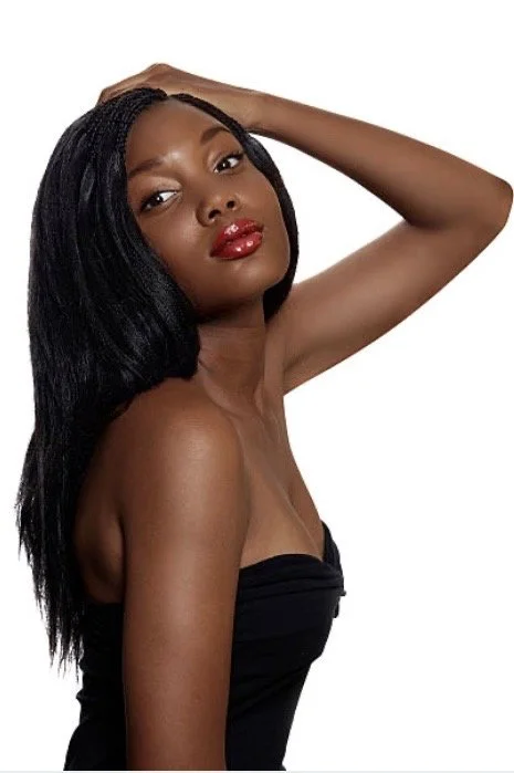 A black woman with dark skin and long black hair wearing sewn in hair extensions
