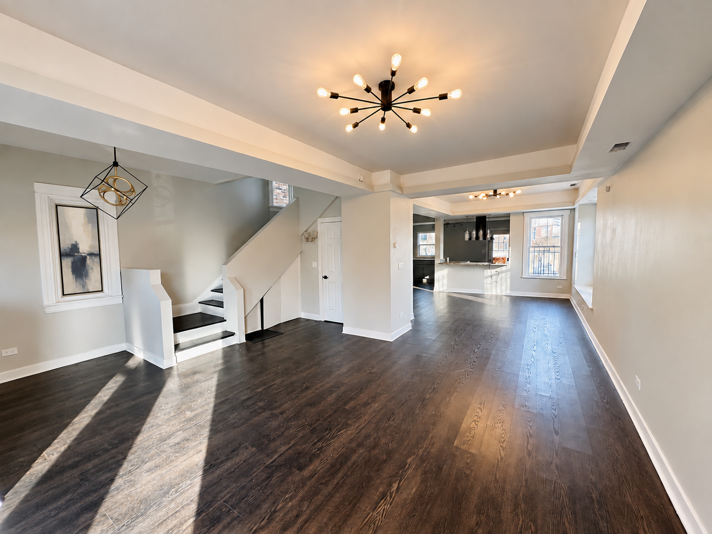 Renovated home interior with dark wood floors, white staircase, and modern lighting; digitally enhanced with artwork added over the covered window.