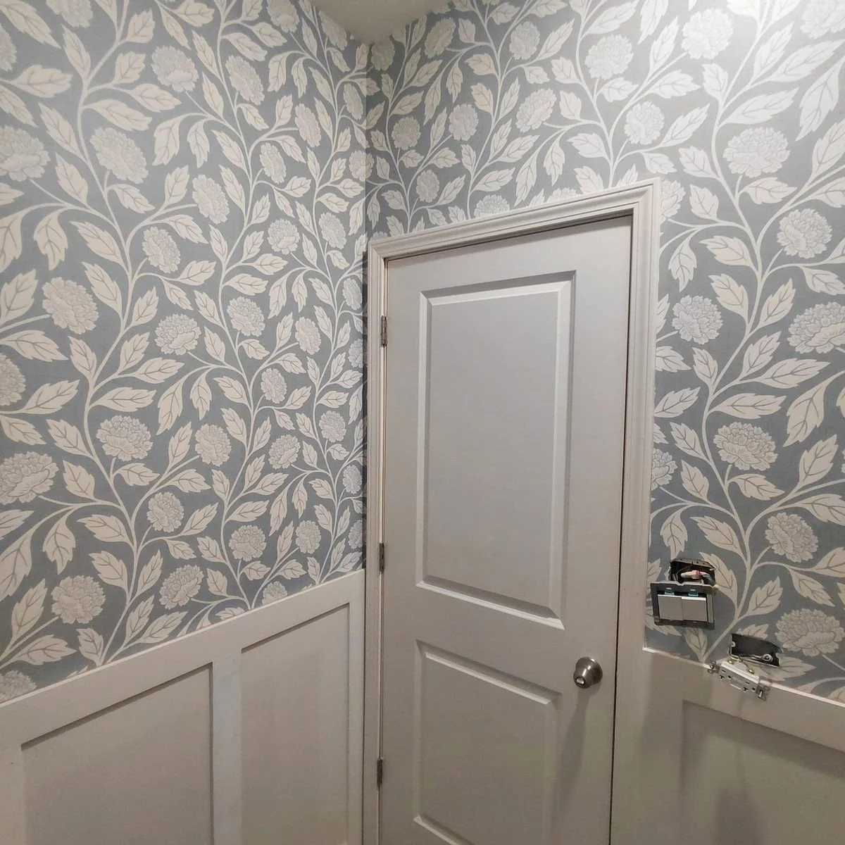 In progress: powder room with patterned wallpaper and wainscoting installed; finish work is ongoing.