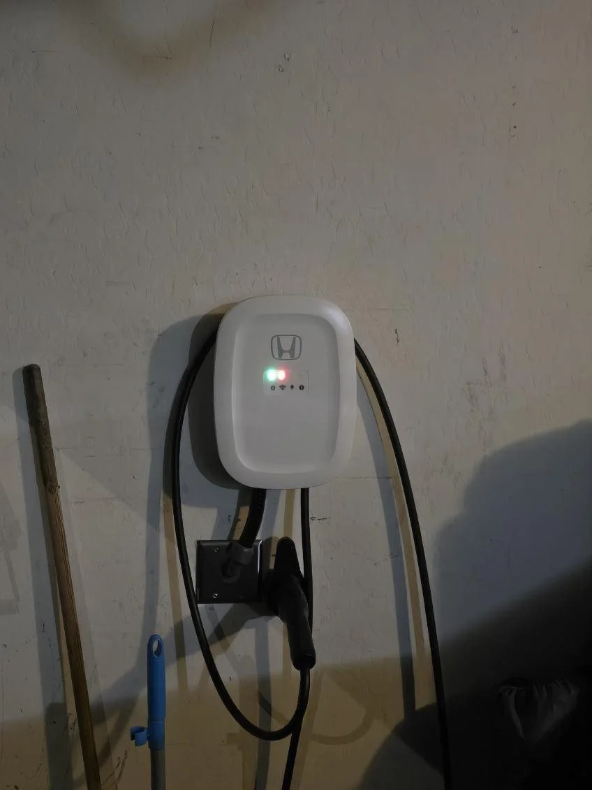 Electric vehicle charging station mounted on a wall with a connected charging cable.