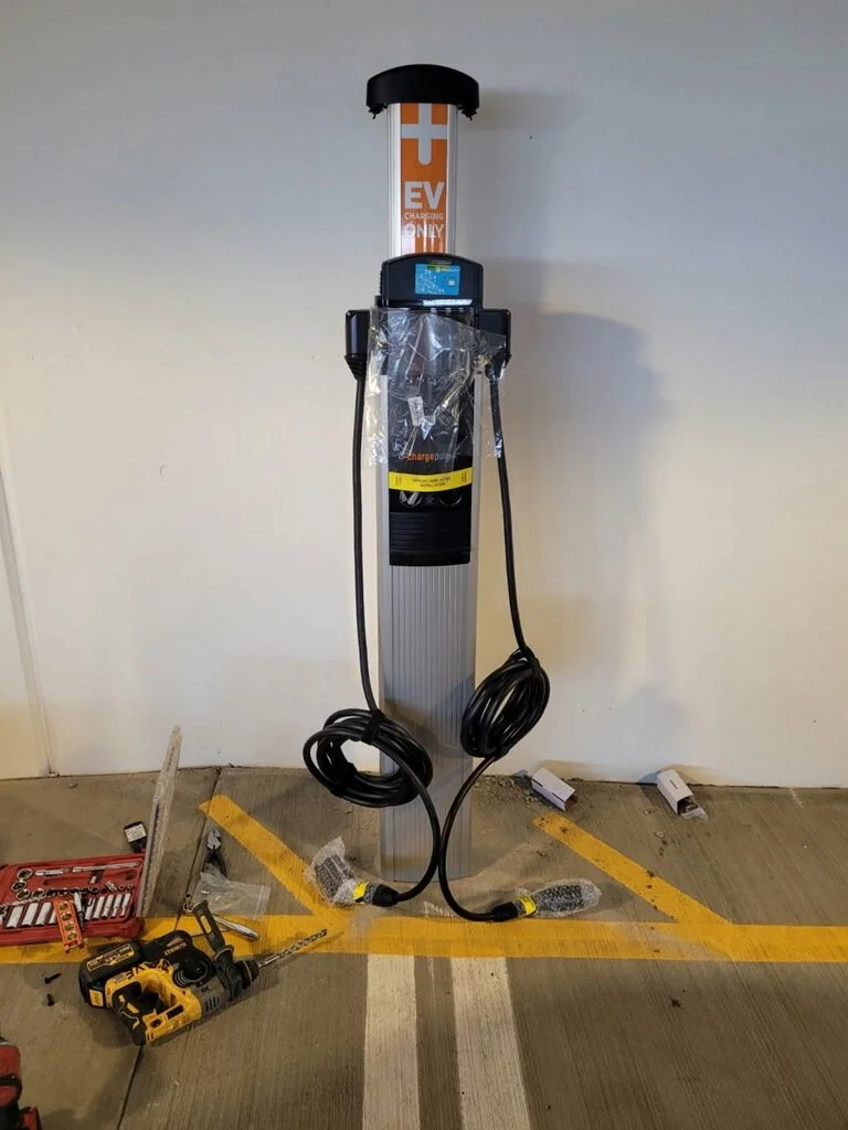 Electric vehicle charging station with tools and accessories on the parking lot ground.