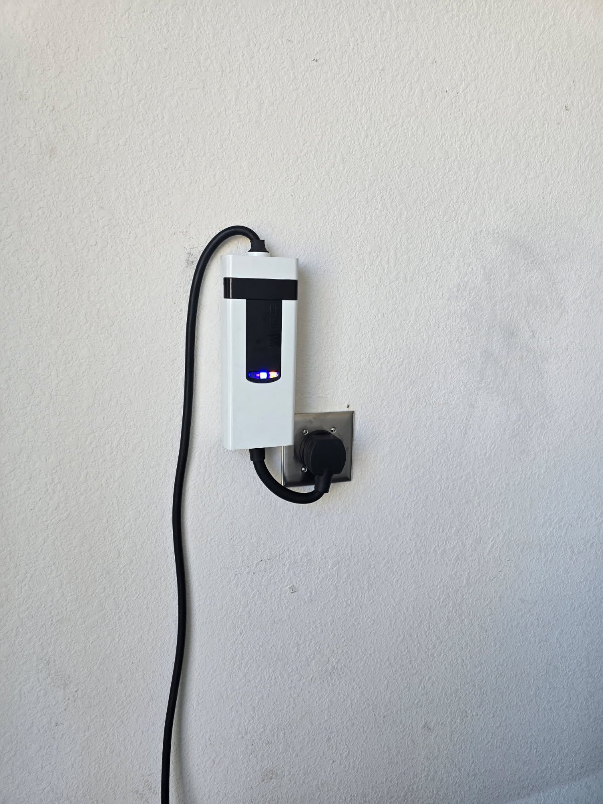 Electric vehicle charging station plugged into wall socket.