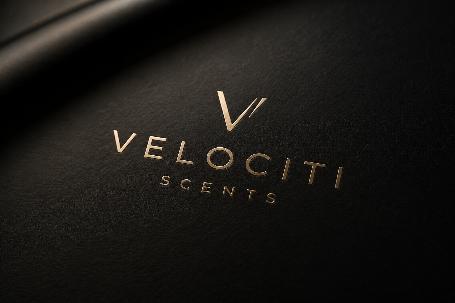 Close-up of a black textured surface with the Velociti Scents logo in gold lettering.