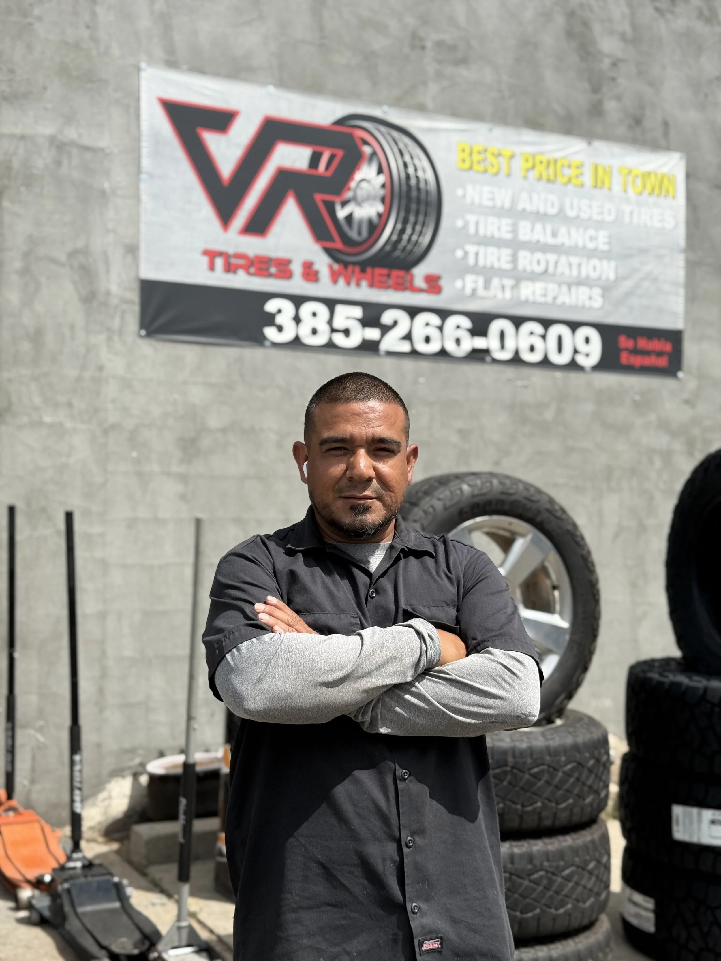 Owner of vr tires, with a large sign advertising tires and wheels in the background.