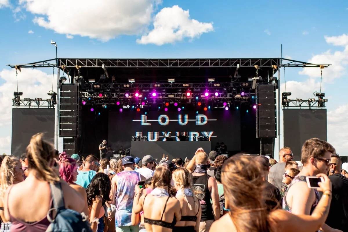A massive festival crowd watching EDM DJ group Loud Luxury perform live at Summer of Sound in Winnipeg, Manitoba.