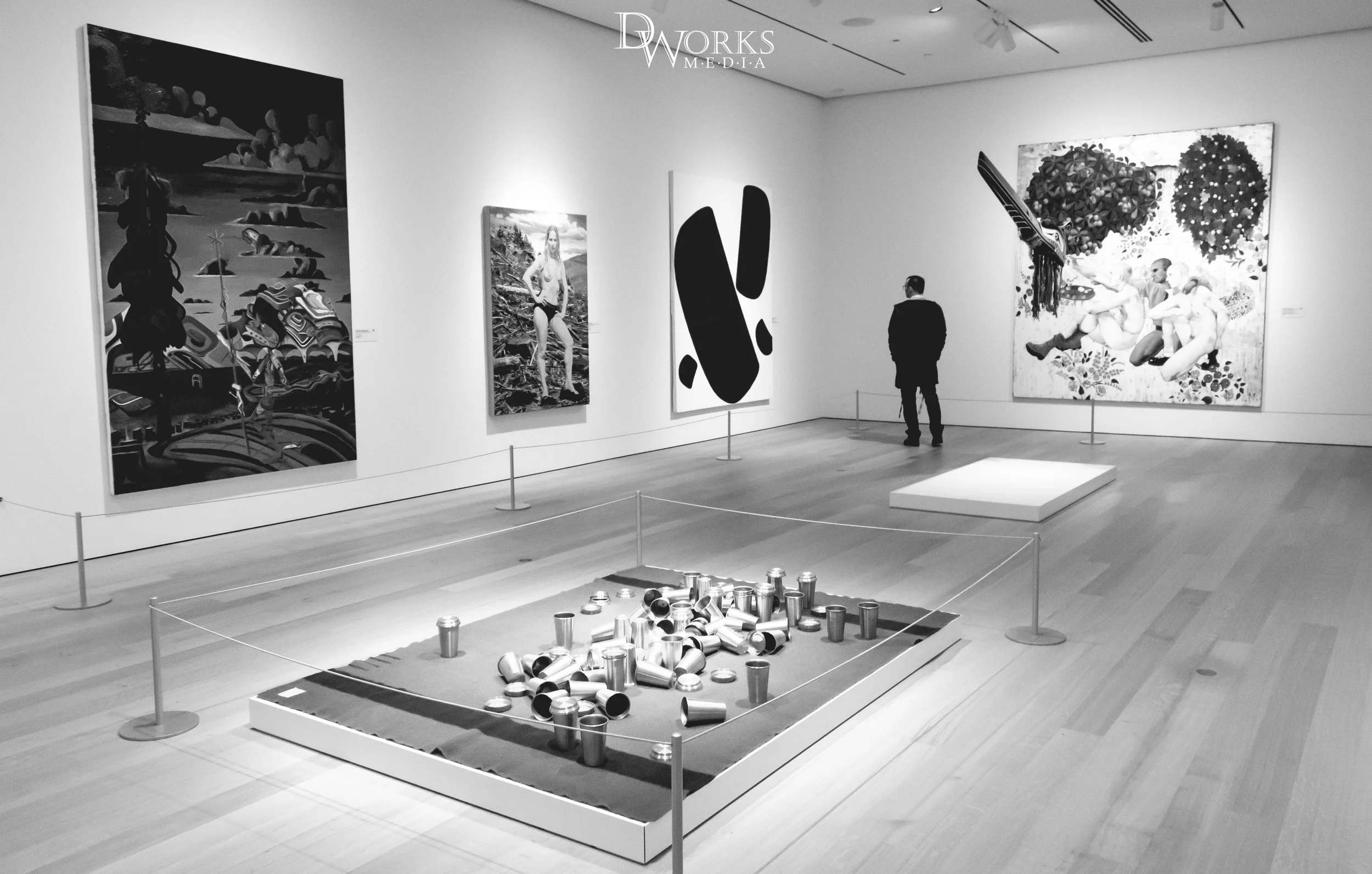 Black and white photography of a solitary man viewing a painting inside an art gallery in Whistler, British Columbia