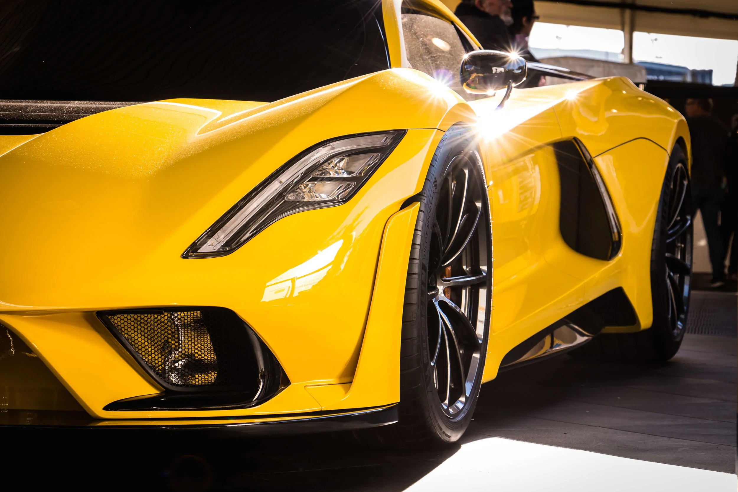 The profile view of a custom yellow sports car parked on display outside the Las Vegas Convention Center during the annual SEMA Show.