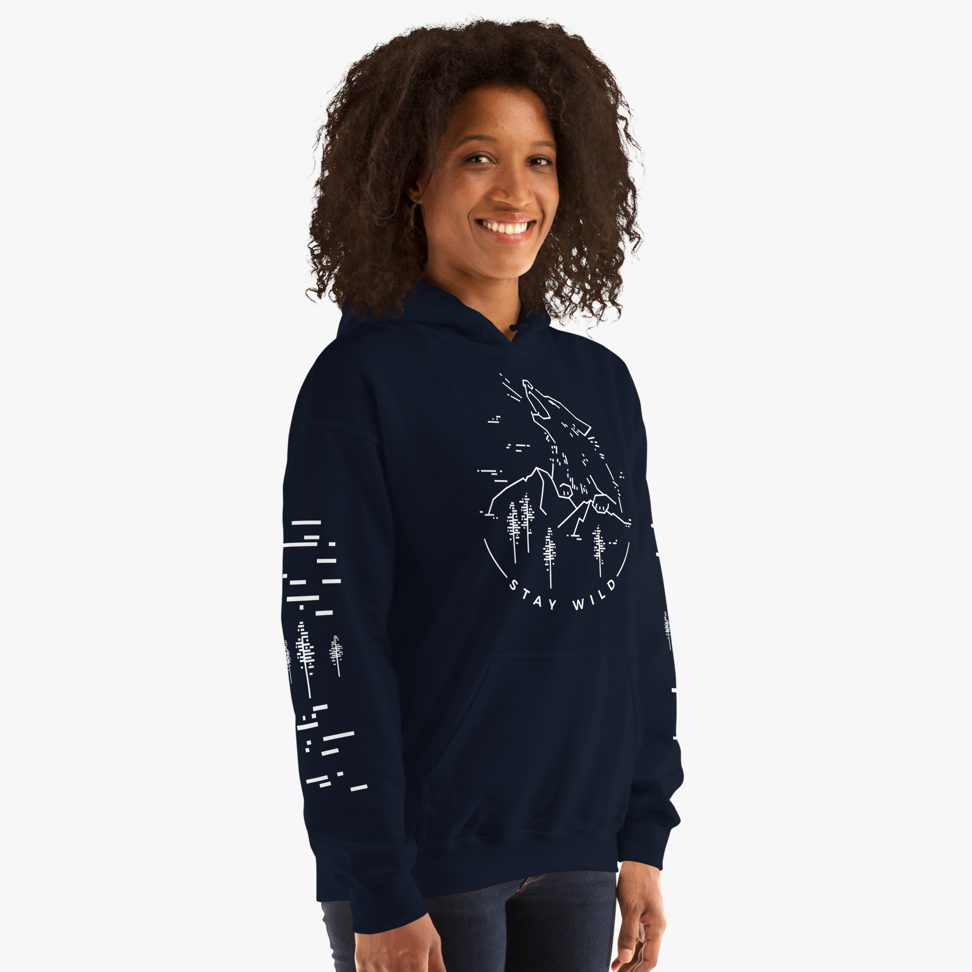 A woman standing and smiling, wearing a dark blue hoodie with a white graphic design on it, and gray pants.