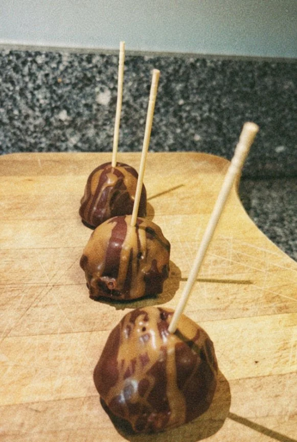 Three chocolate dipped apple bites with a salted caramel drizzle
