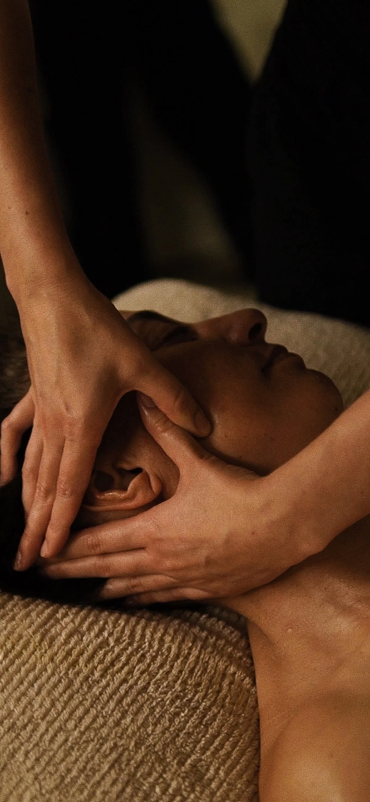 Person receiving a massage or facial treatment, with hands gently massaging or applying pressure to their face.