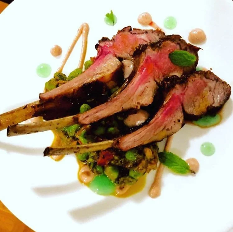 Herb-crusted roasted lamb chops plated for in-home dinner party