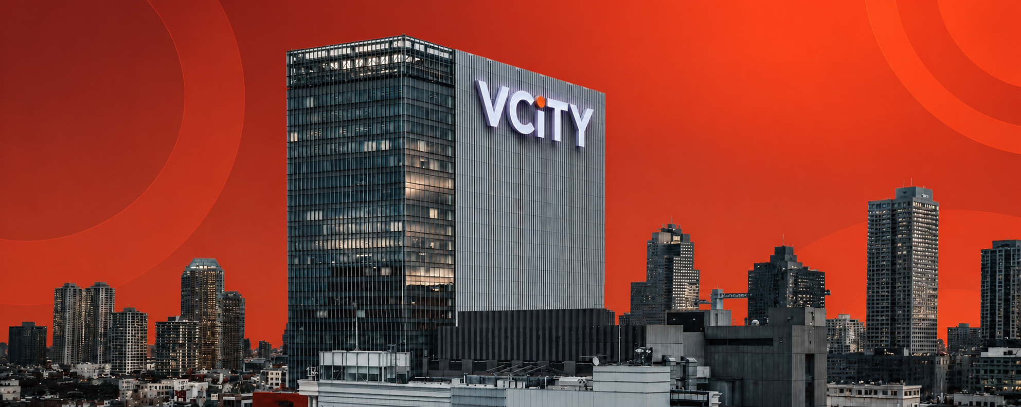 A tall modern skyscraper with the logo 'VCITY' on it, set against an orange sky, surrounded by other high-rise buildings in a city skyline.