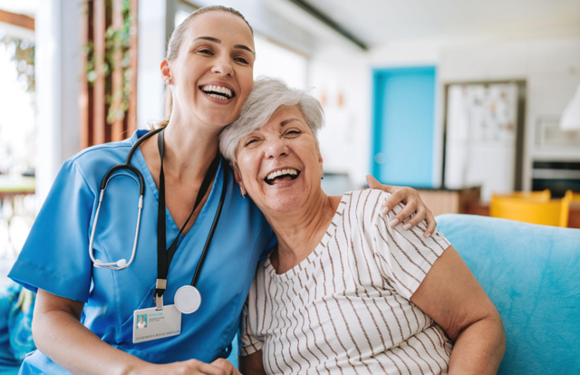 A healthcare professional hugging an elderly woman in a bright medical facility.