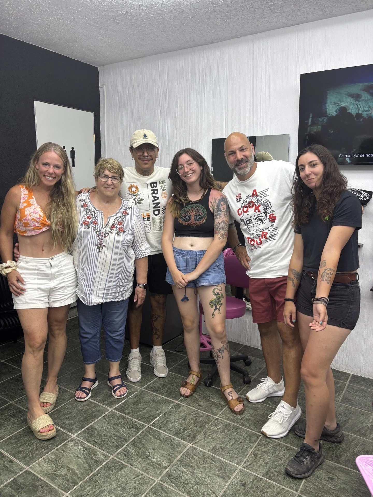 Seven people standing together in a room, posing for a group photo, smiling at the camera.