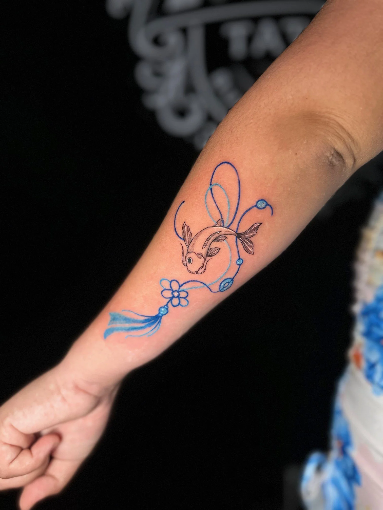 Close-up of a person's forearm with a colorful tattoo of a rabbit with flowers and swirling lines in blue, purple, and brown ink.