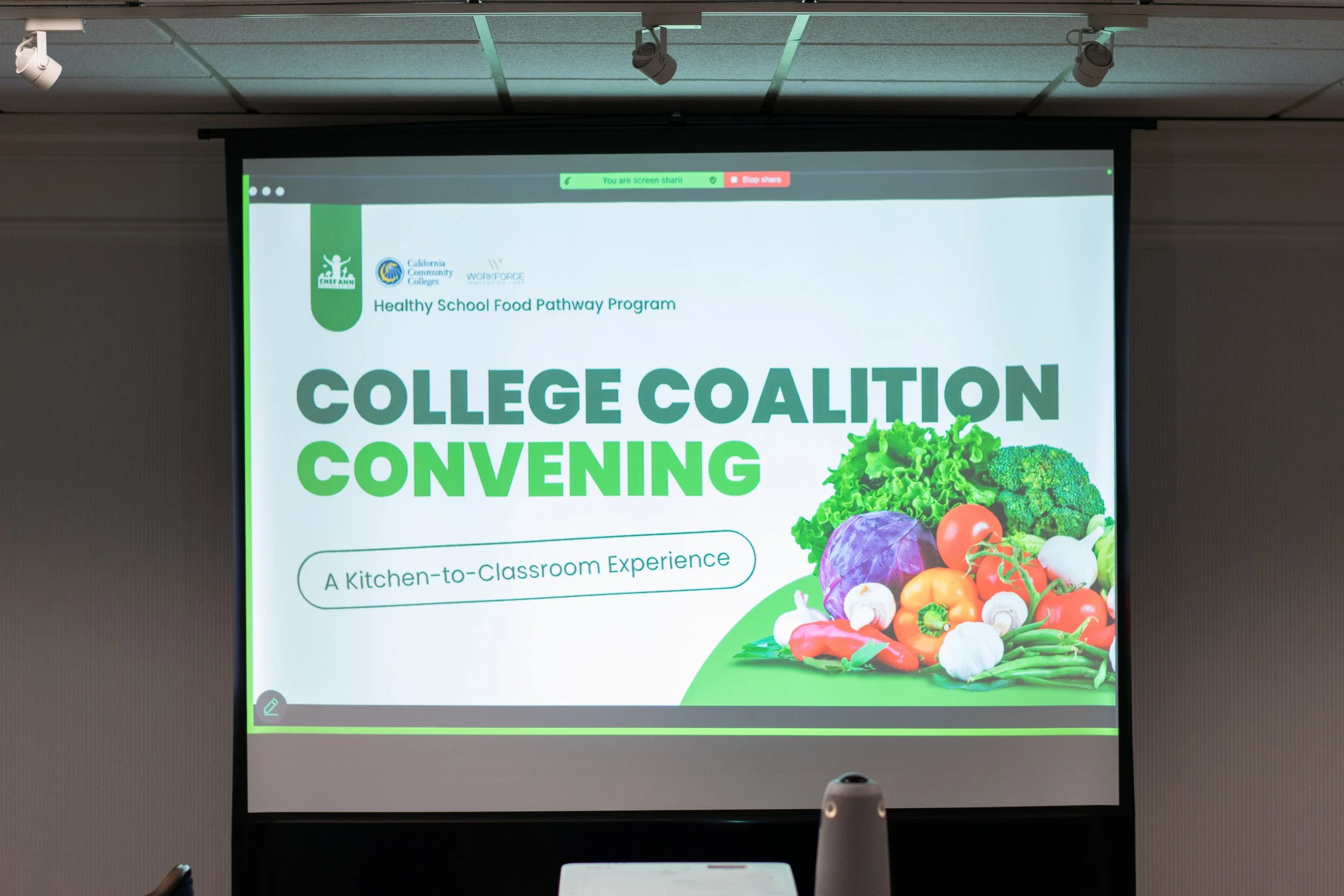 Presentation screen displaying information about the 'Healthy School Food Pathway Program' with logos of California Community Colleges and Workforce, and a colorful image of vegetables.