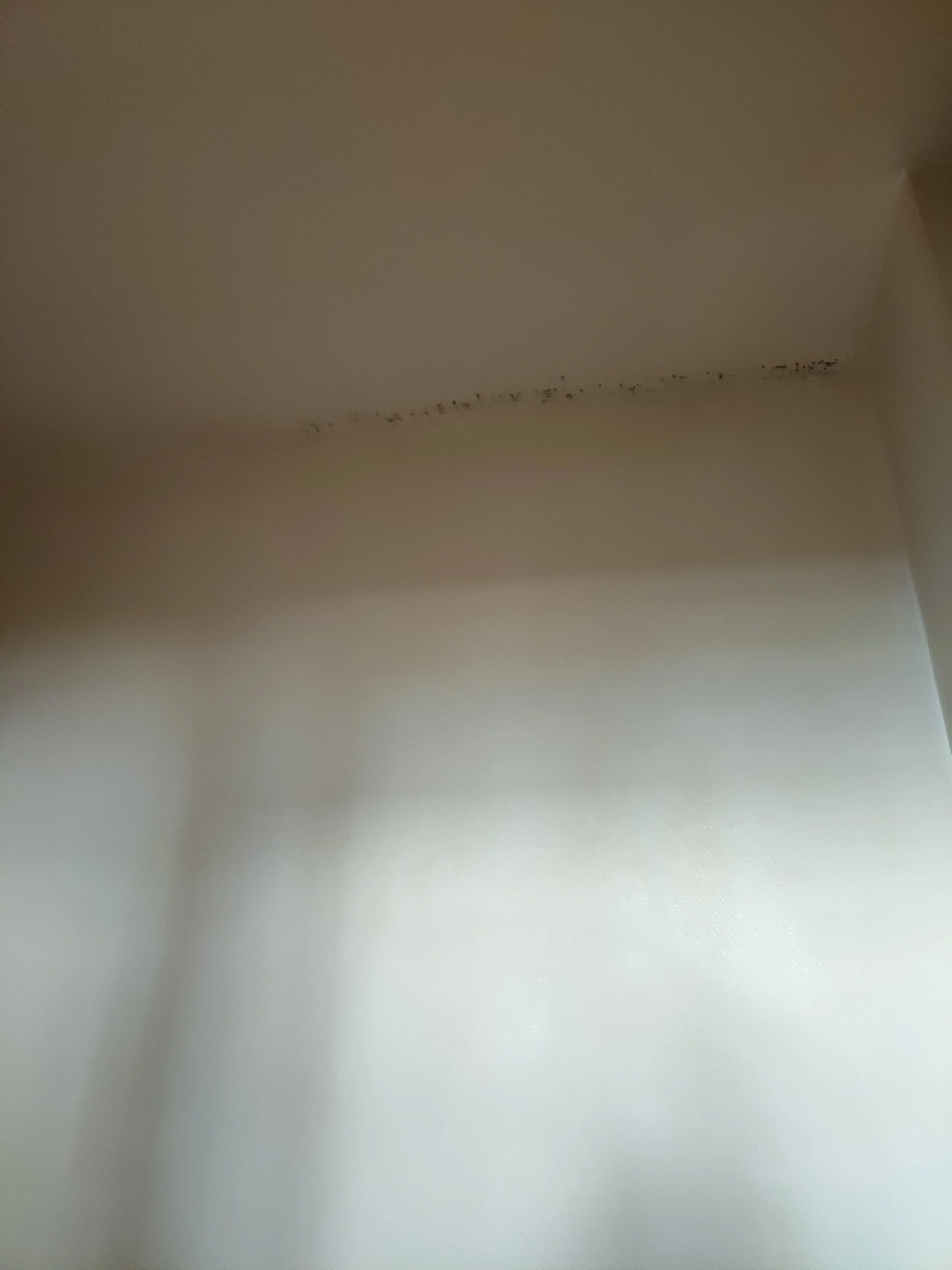 Le plafond d'une pièce avec une ligne de traces noires ou de moisissures.