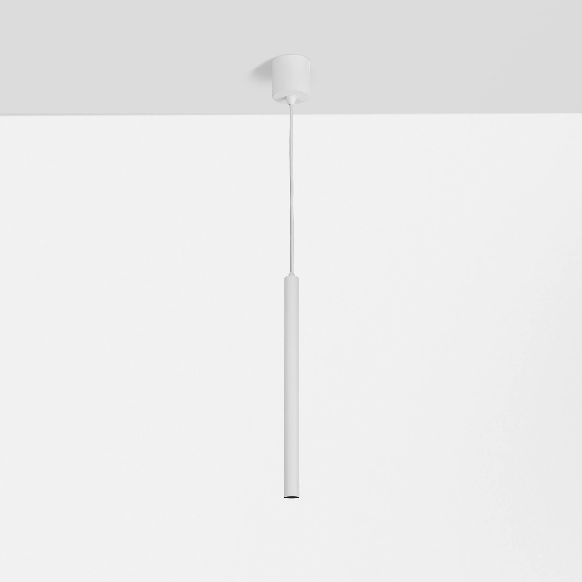 Een witte kabel met een plafondstop contact bevestigd aan een witte muur.