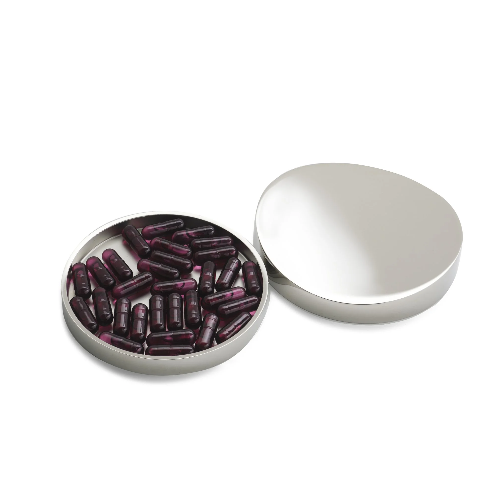Een witte ronde doos gevuld met donkere capsules, naast een lege witte doos.