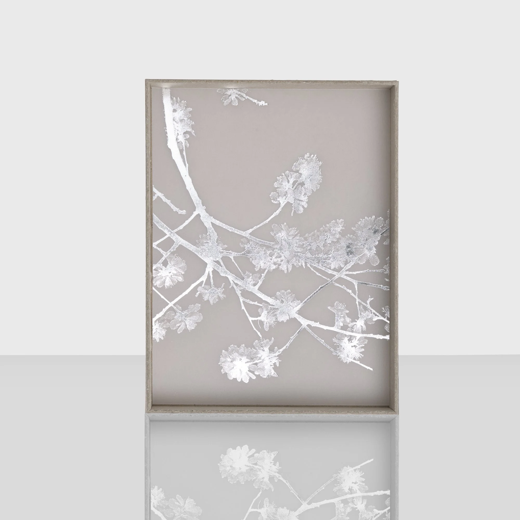 Een witte lijst met een bloemmotief op een lichtgrijze achtergrond.