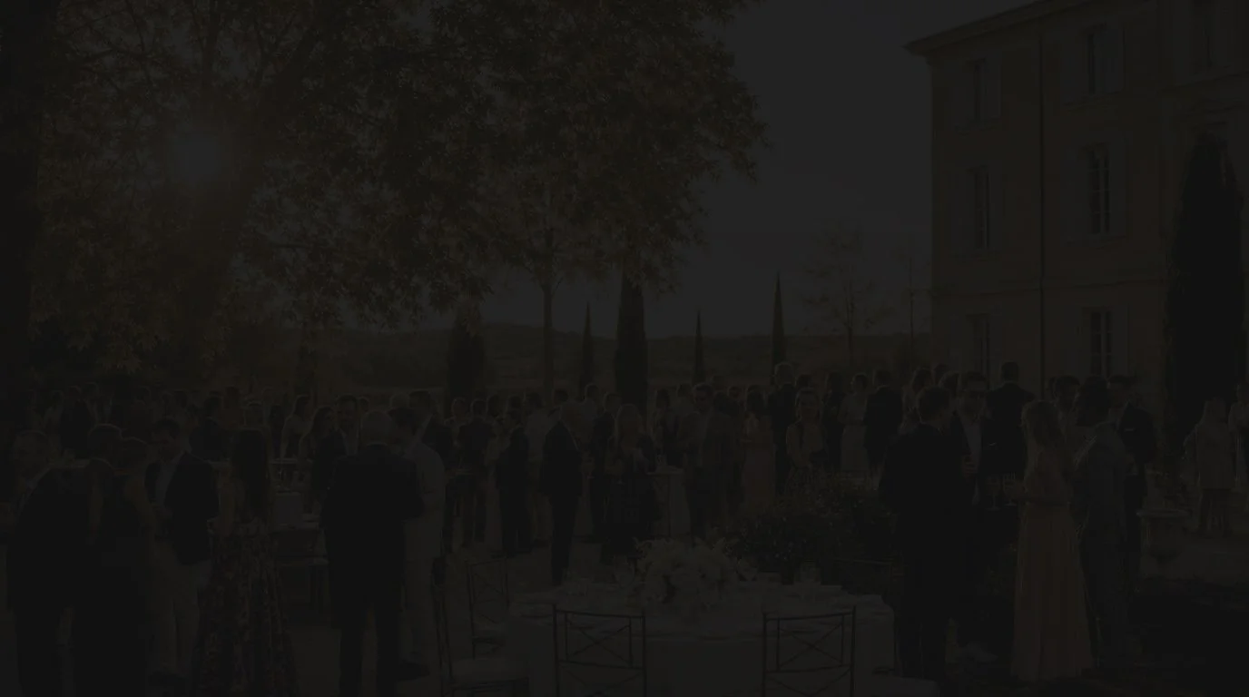 Invités réunis lors d’une réception élégante en extérieur à la tombée de la nuit.