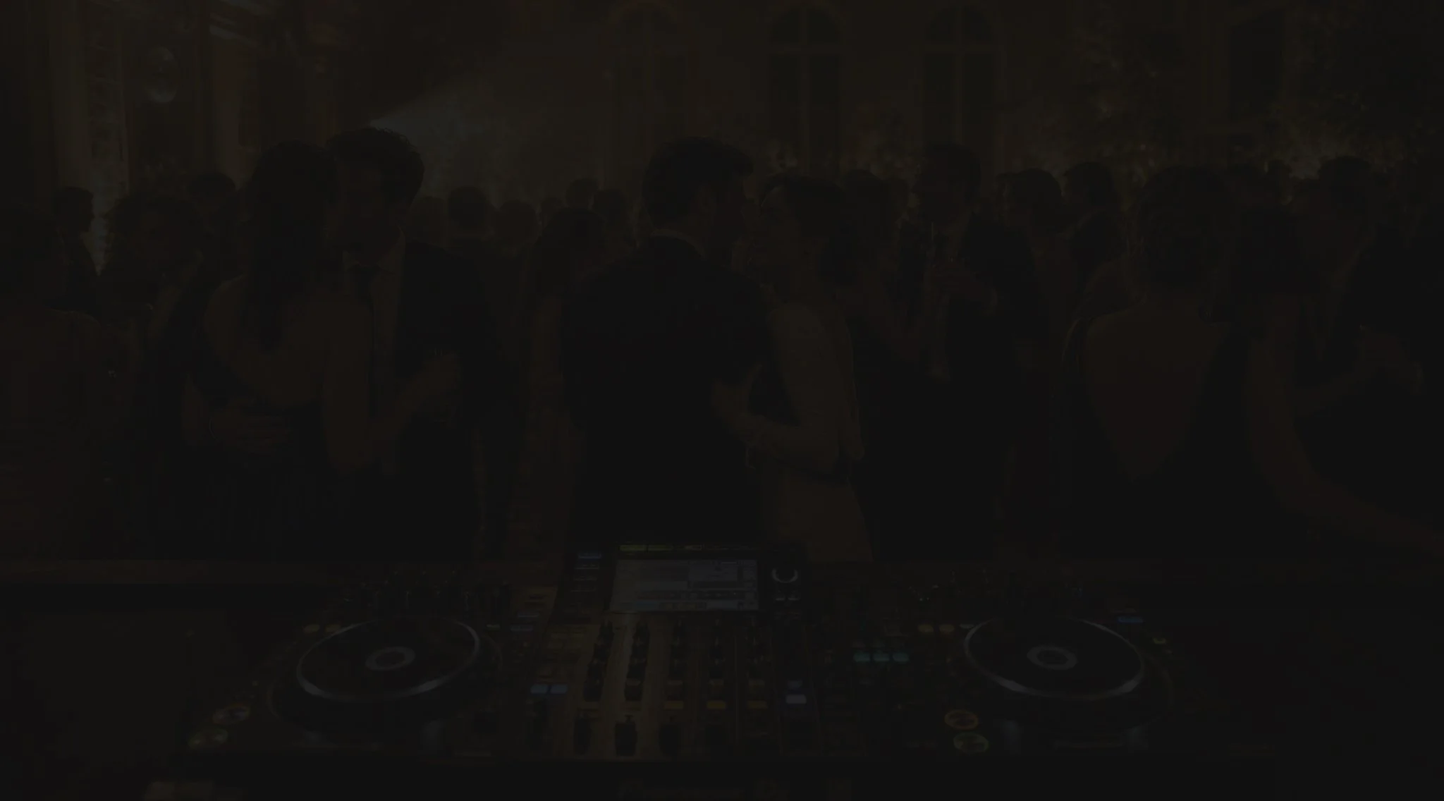 Régie DJ au premier plan face à une piste de danse animée lors d’une réception.