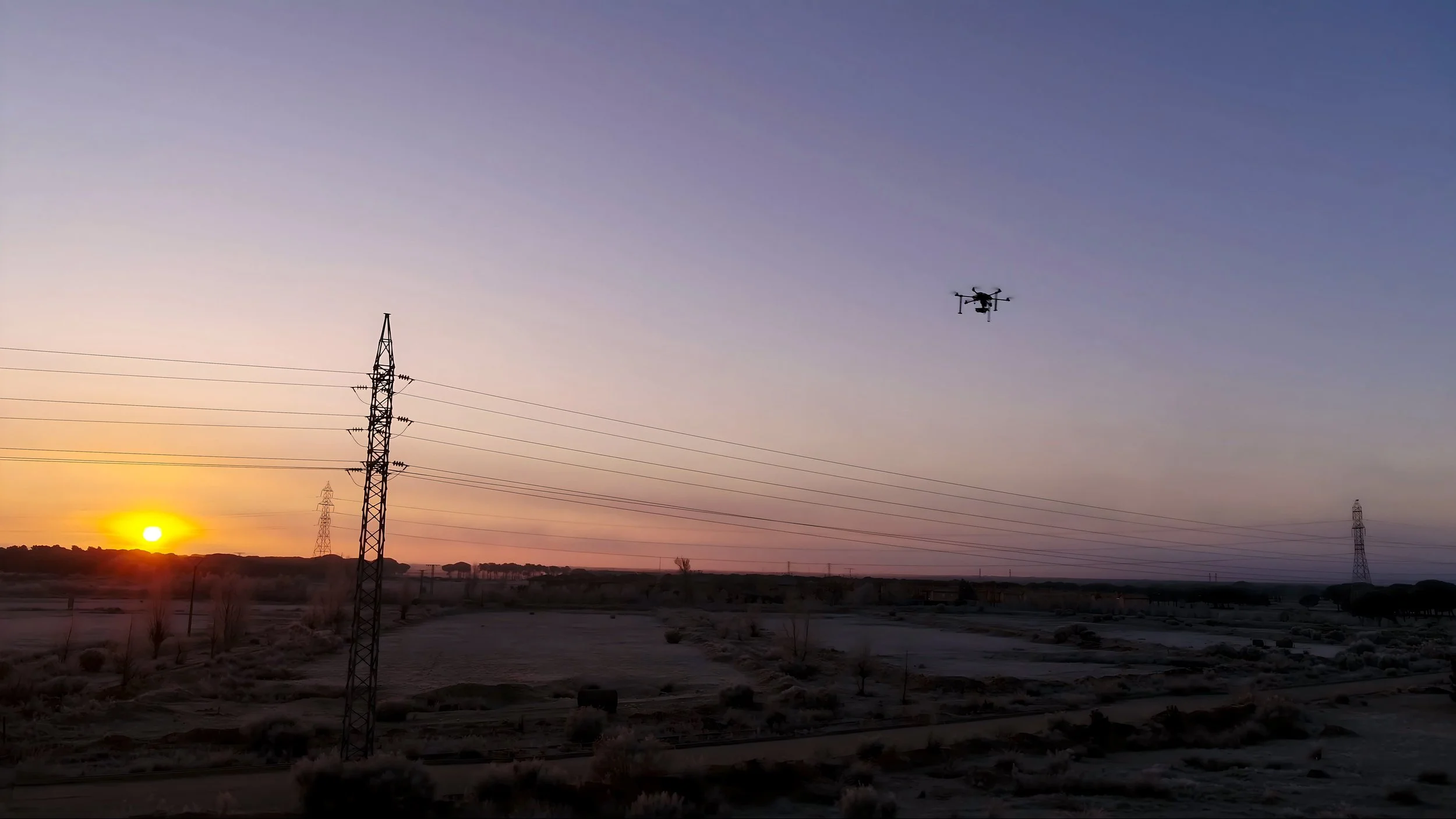 Utility drone inspecting overhead electrical infrastructure using thermal and visual imaging.