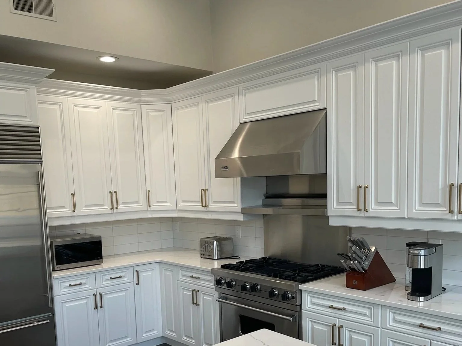 Kitchen with refinished white cabinetry, granite countertops, stainless steel appliances, and a tiled backsplash.
