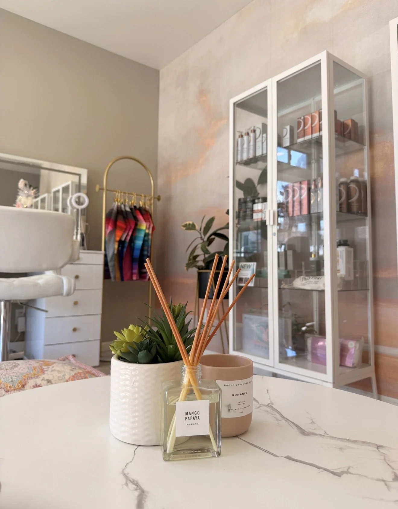 Inside the Chrissy Jacobs Esthetics studio, with a color analysis drape rack, candles, and skincare display