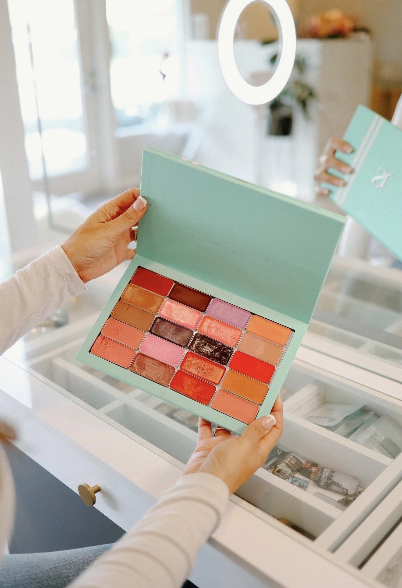 Hands holding an eyeshadow palette with warm and cool shades, picked to match your coloring in a makeup consultation in Aptos California