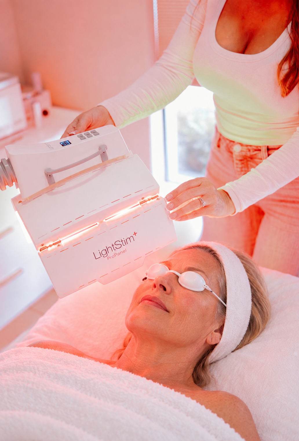 Esthetician adjusting a LightStim LED panel during a relaxing light therapy facial in Santa Cruz