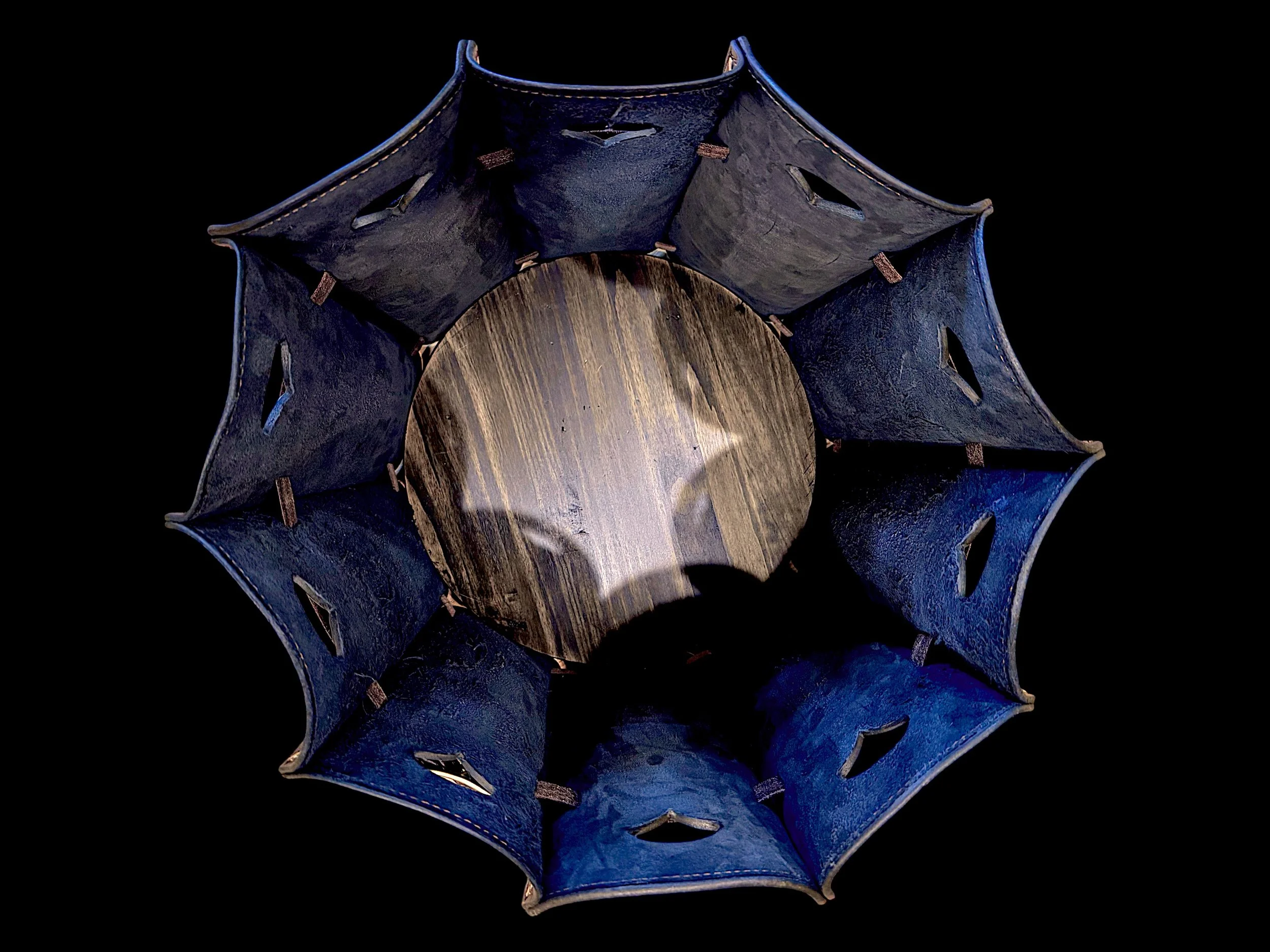 A spherical object with a intricate structure, consisting of blue and brown parts, appears to be made of wood and metal, with a black background.