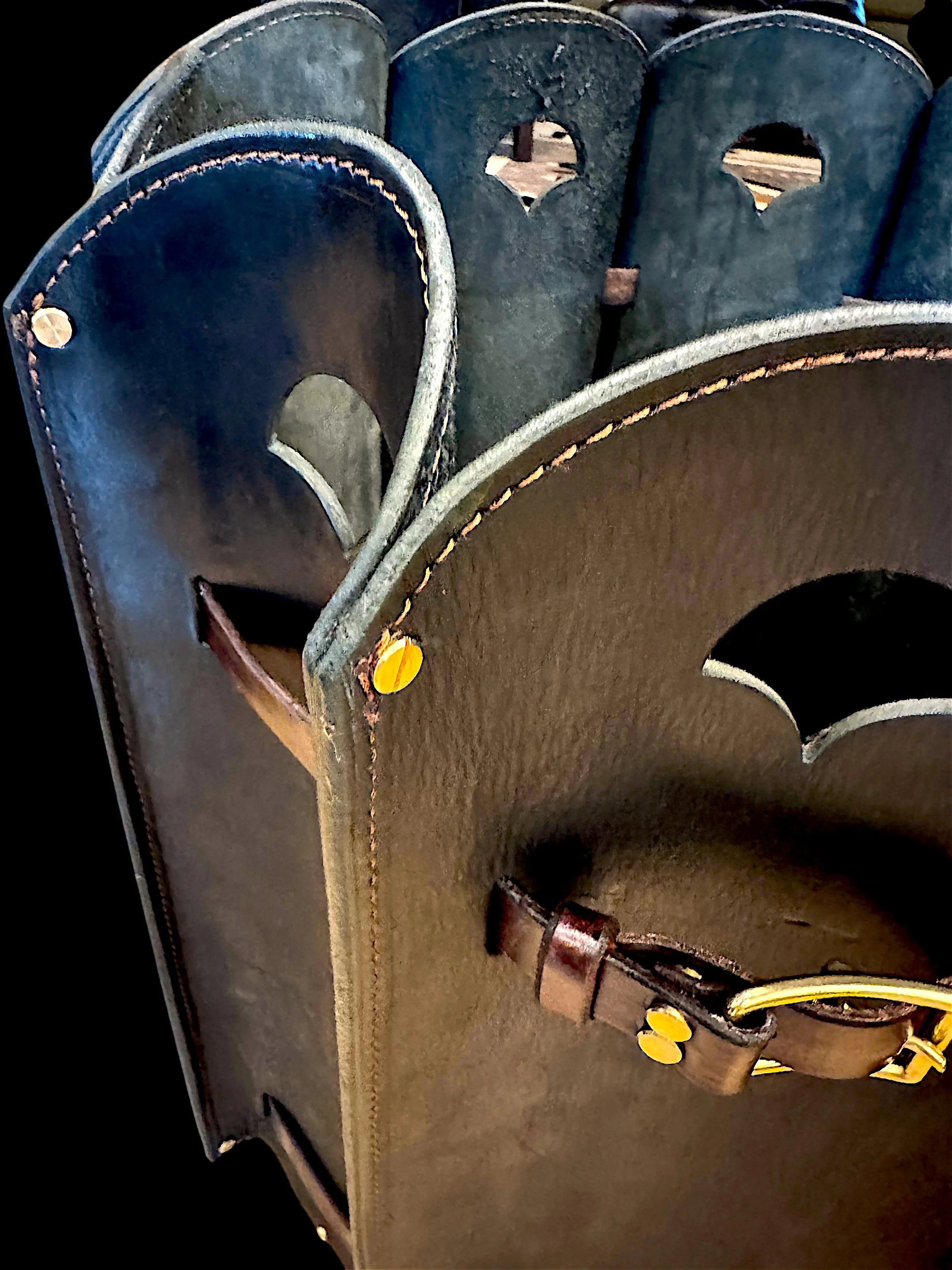 Close-up of a baseball glove with black leather and yellow laces, resting on a brown leather surface.